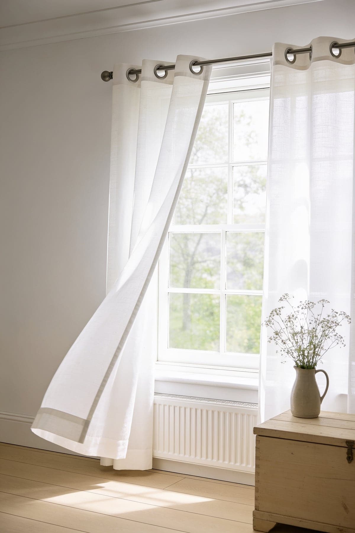 The white voile curtains lifting in a breeze at an open sash window