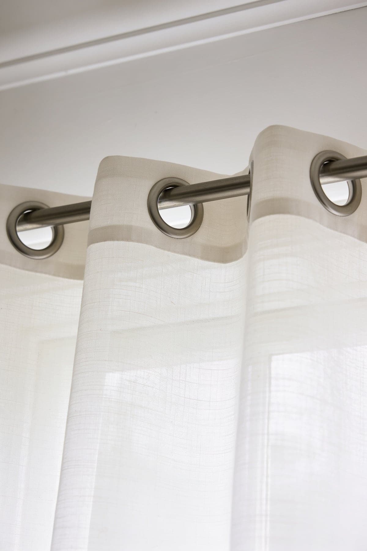 Close up of the voile curtains' eyelet heading and slub weave on a metal pole
