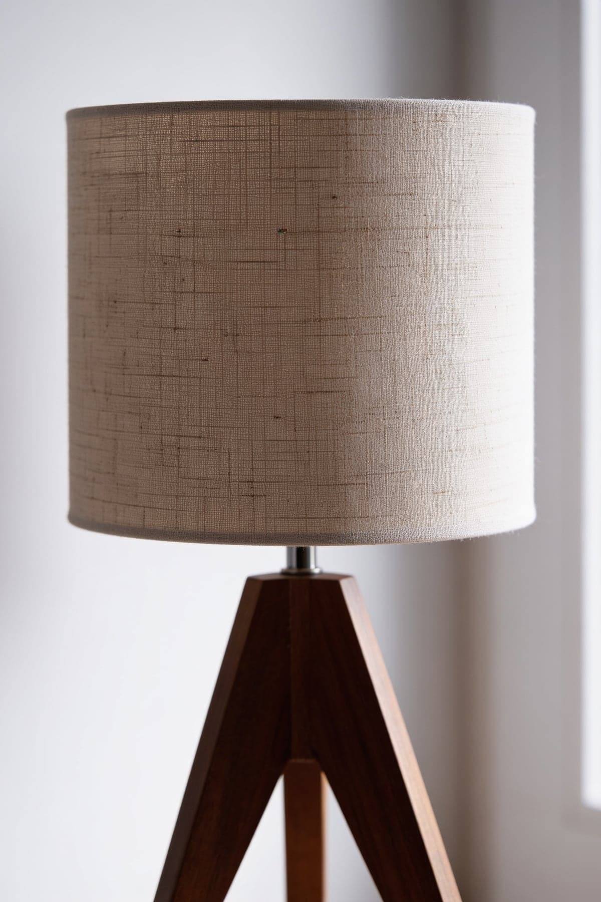 Close up of the tripod lamp's linen drum shade and walnut legs