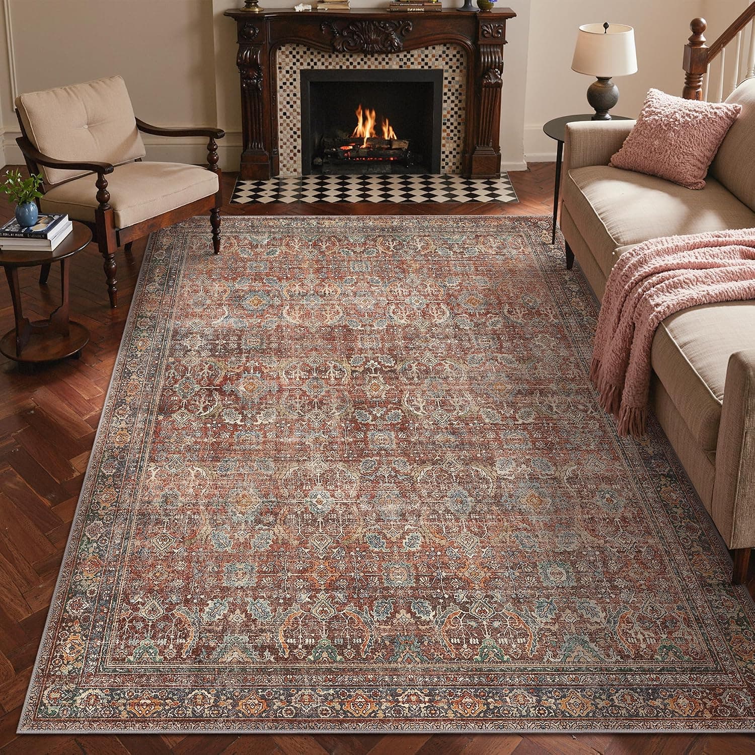 A flat-woven rectangular rug in faded terracotta with a floral, leaf and bird pattern inside ochre and brown borders