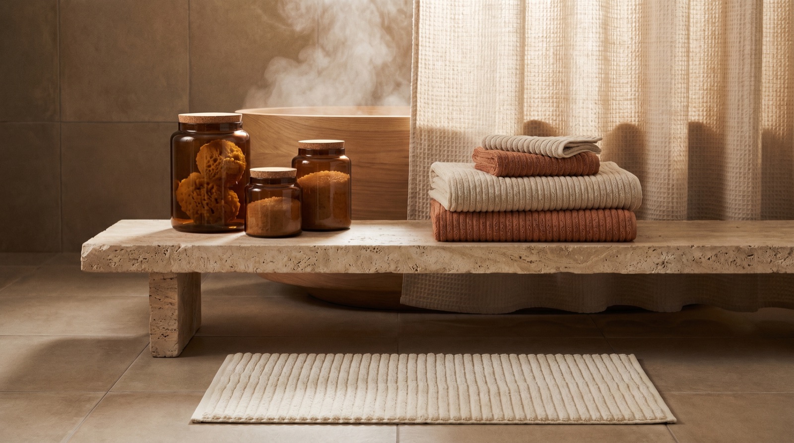 A serene coastal bathroom — waffle-weave textures, a soft cotton rug, ceramic storage and warm diffused light on stone